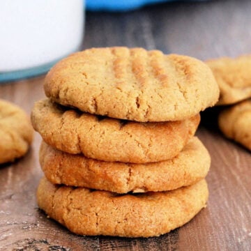 Stack of air fryer peanut butter cookies near a glass of milk and blue napkin.