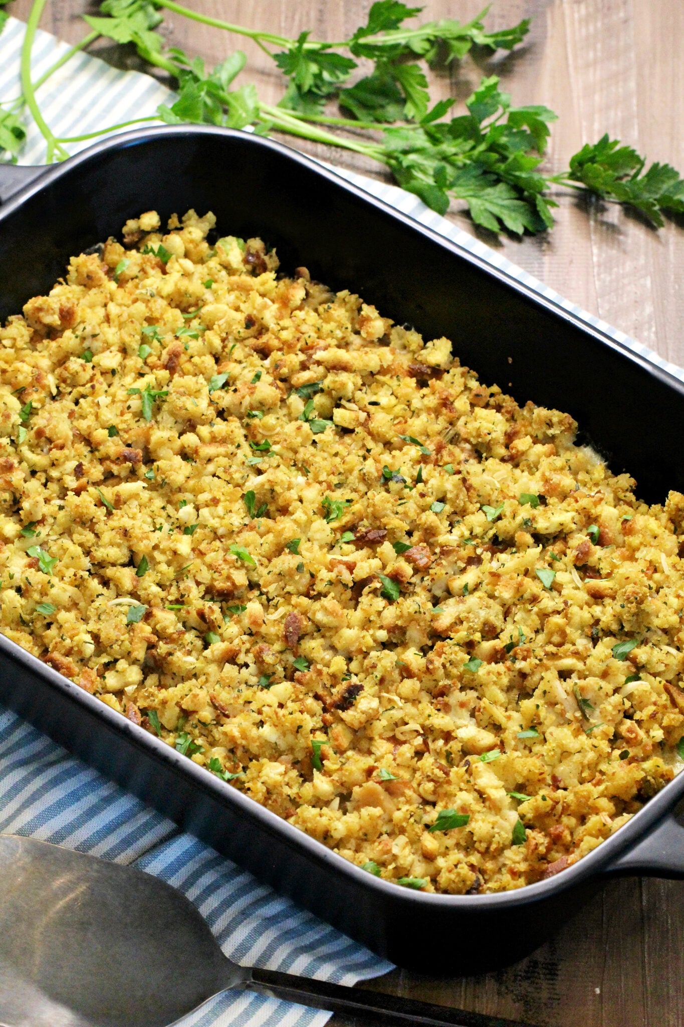 Turkey and Stuffing Casserole in a black baking dish with parsley nearby.