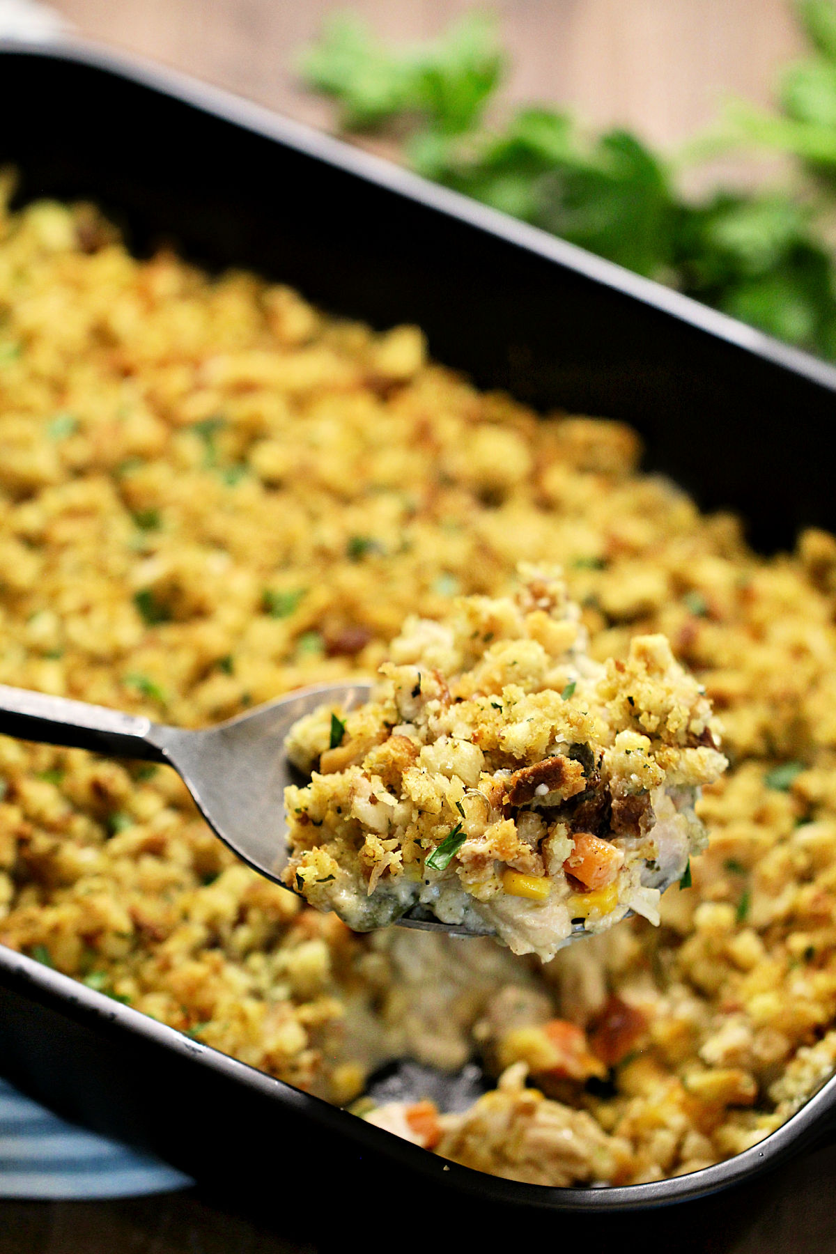 A scoop of Turkey and Stuffing Casserole on a metal serving spoon.