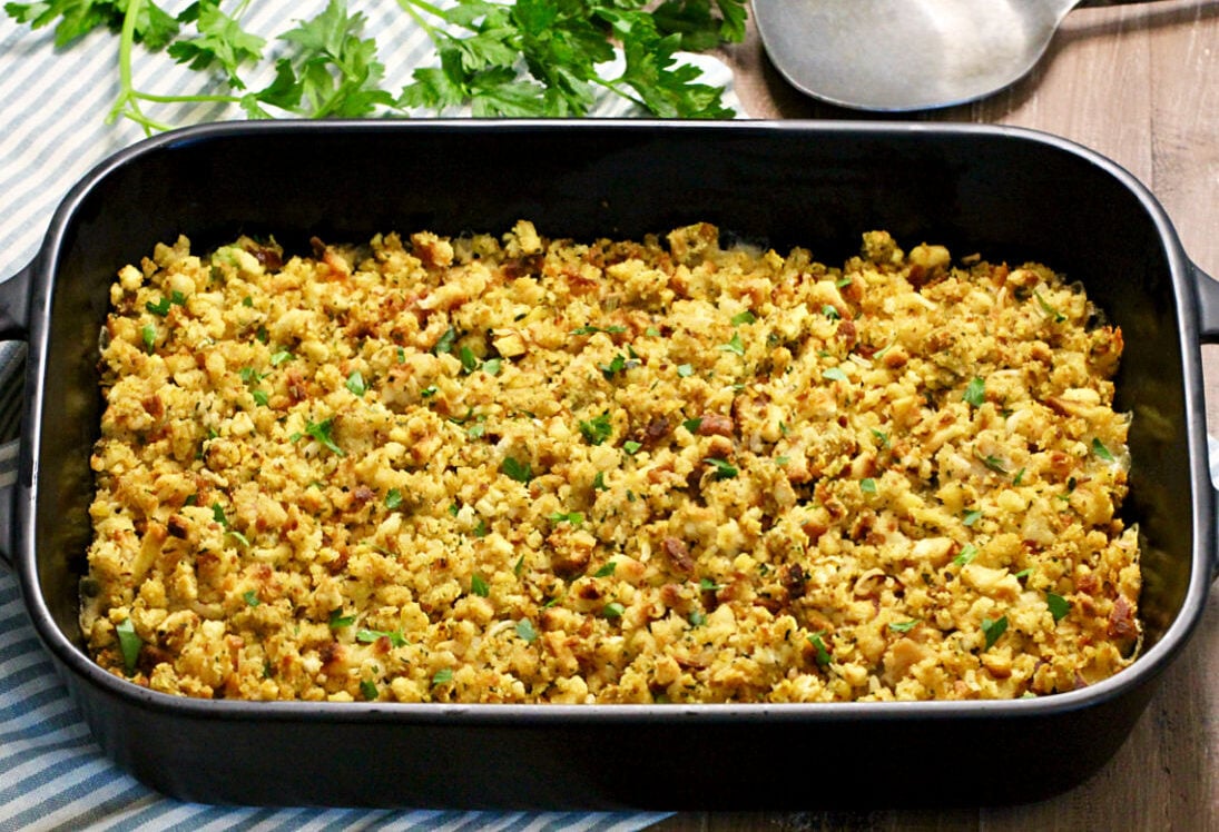 Turkey and Stuffing Casserole in a black baking dish with parsley nearby.