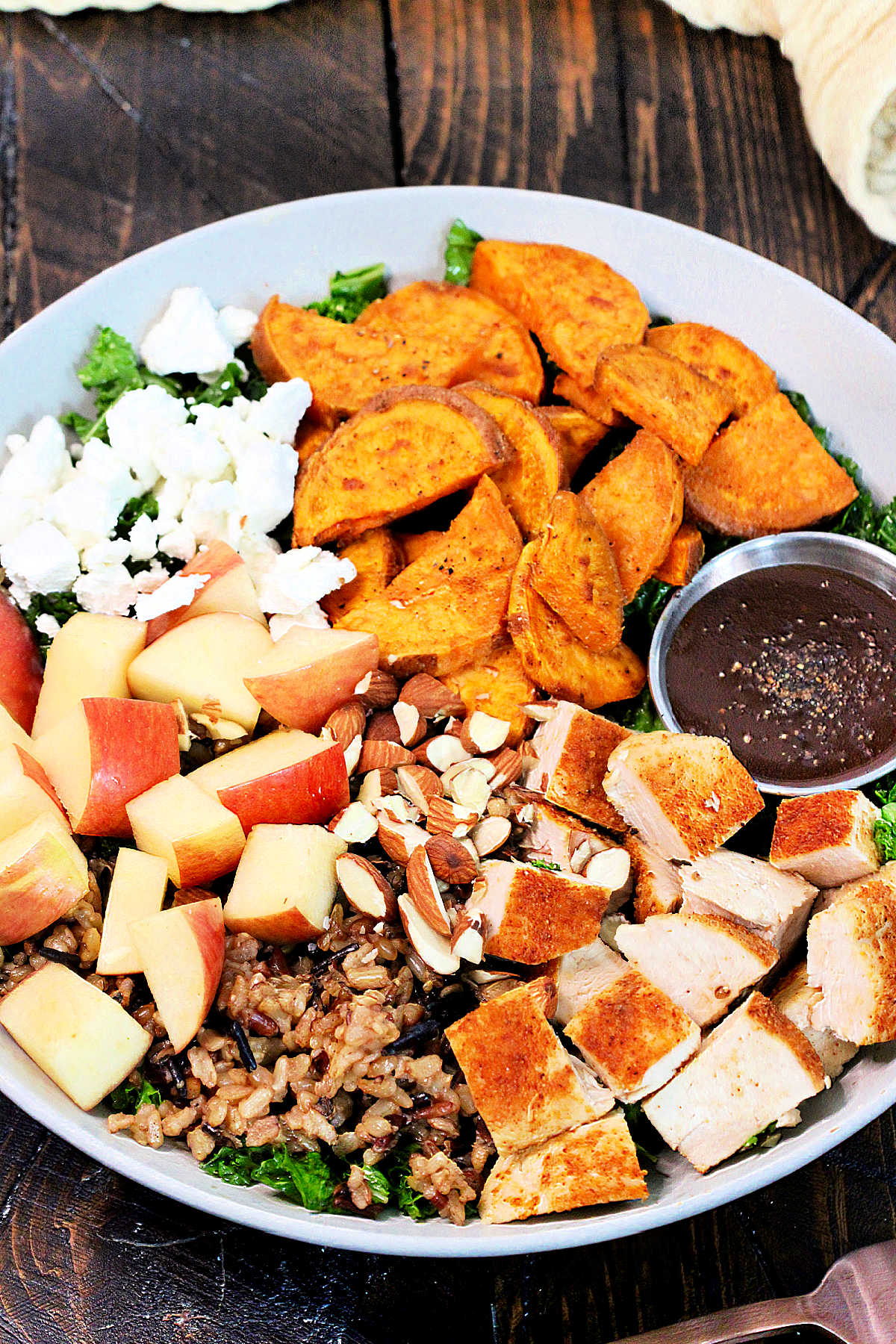 Harvest bowl with a side of vinaigrette in a white bowl on a wooden board.