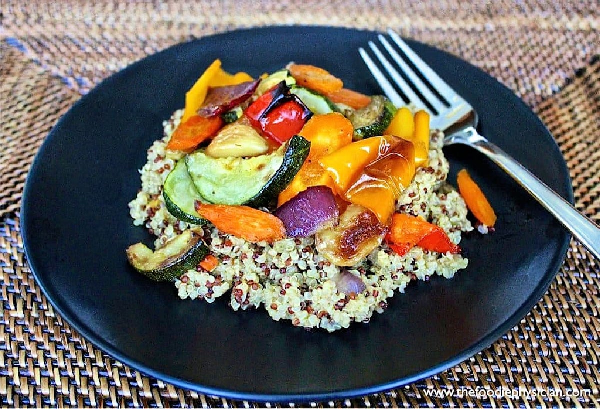The perfect oven-roasted vegetables with quinoa on a black plate.