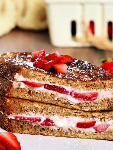 Two pieces of strawberry stuffed French toast stacked on a white plate.