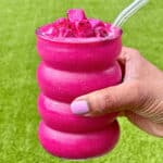 Dragon fruit smoothie in a bubble glass being held outside.