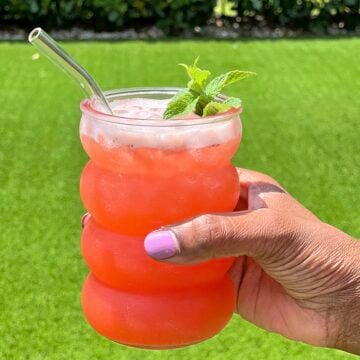 A glass of strawberry pineapple lemonade being held outside