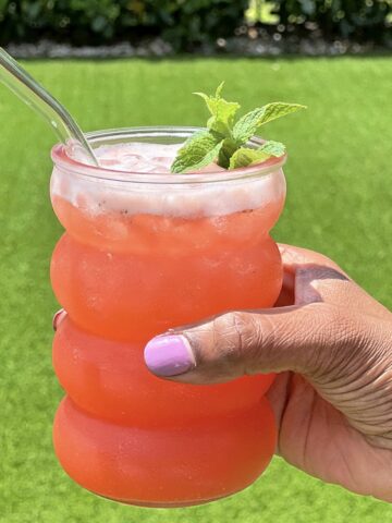 A glass of strawberry pineapple lemonade being held outside