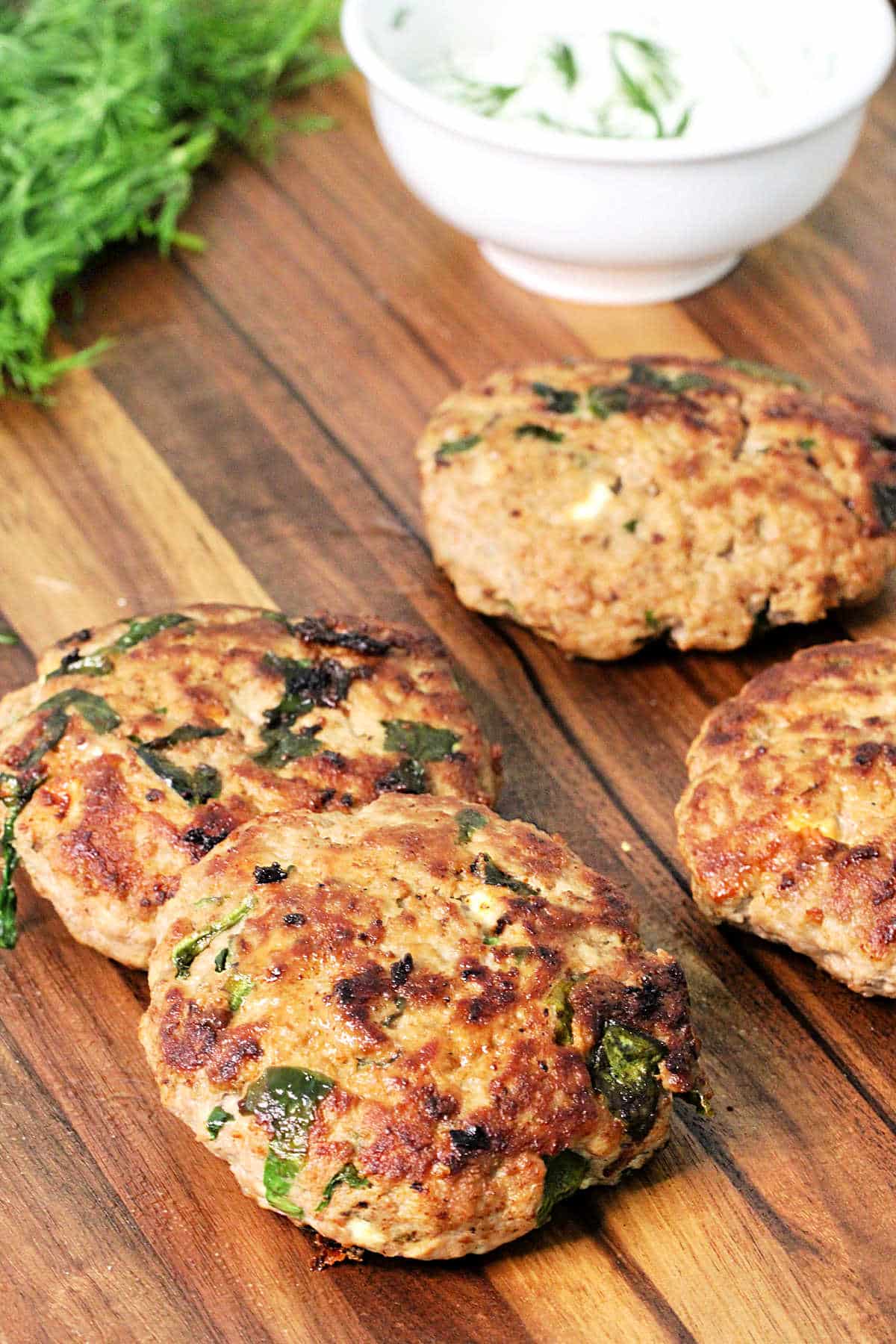 Greek turkey burger patties on a cutting board.