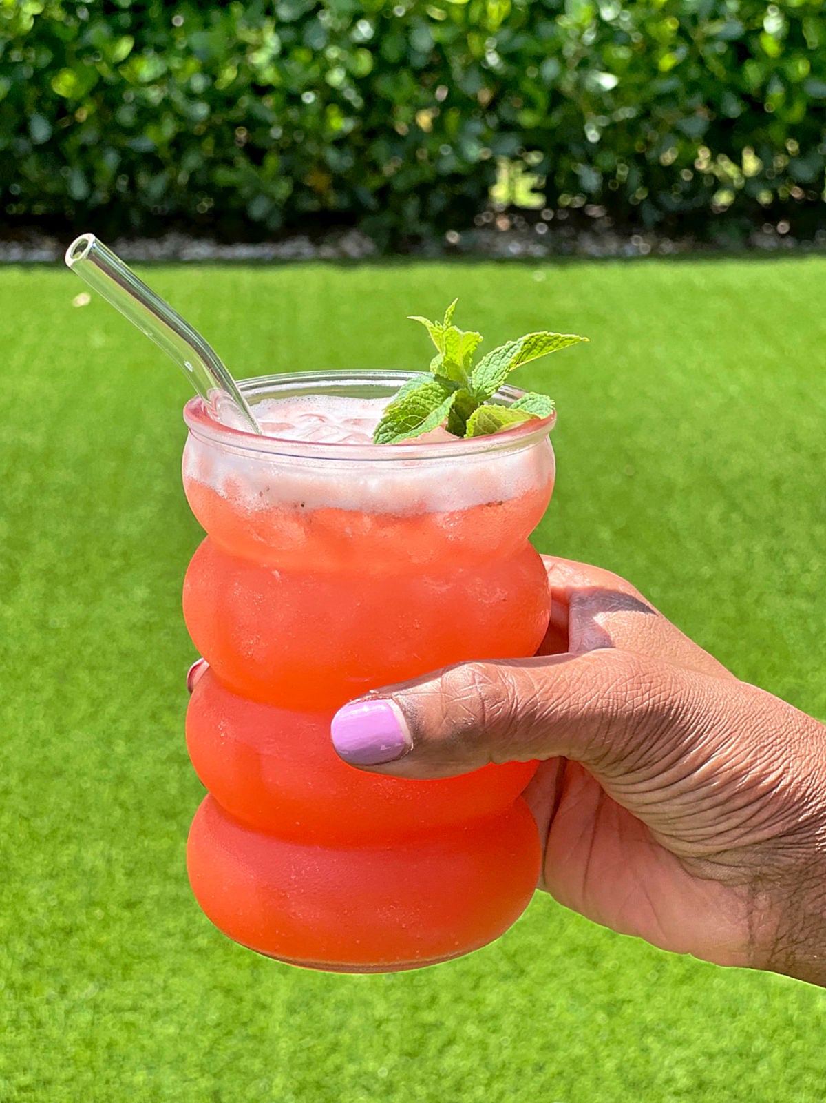 A glass of strawberry pineapple lemonade being held outside
