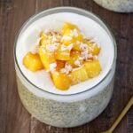 Mango Chia Pudding in a glass jar with a gold spoon nearby.
