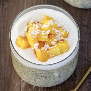 Mango Chia Pudding in a glass jar with a gold spoon nearby.