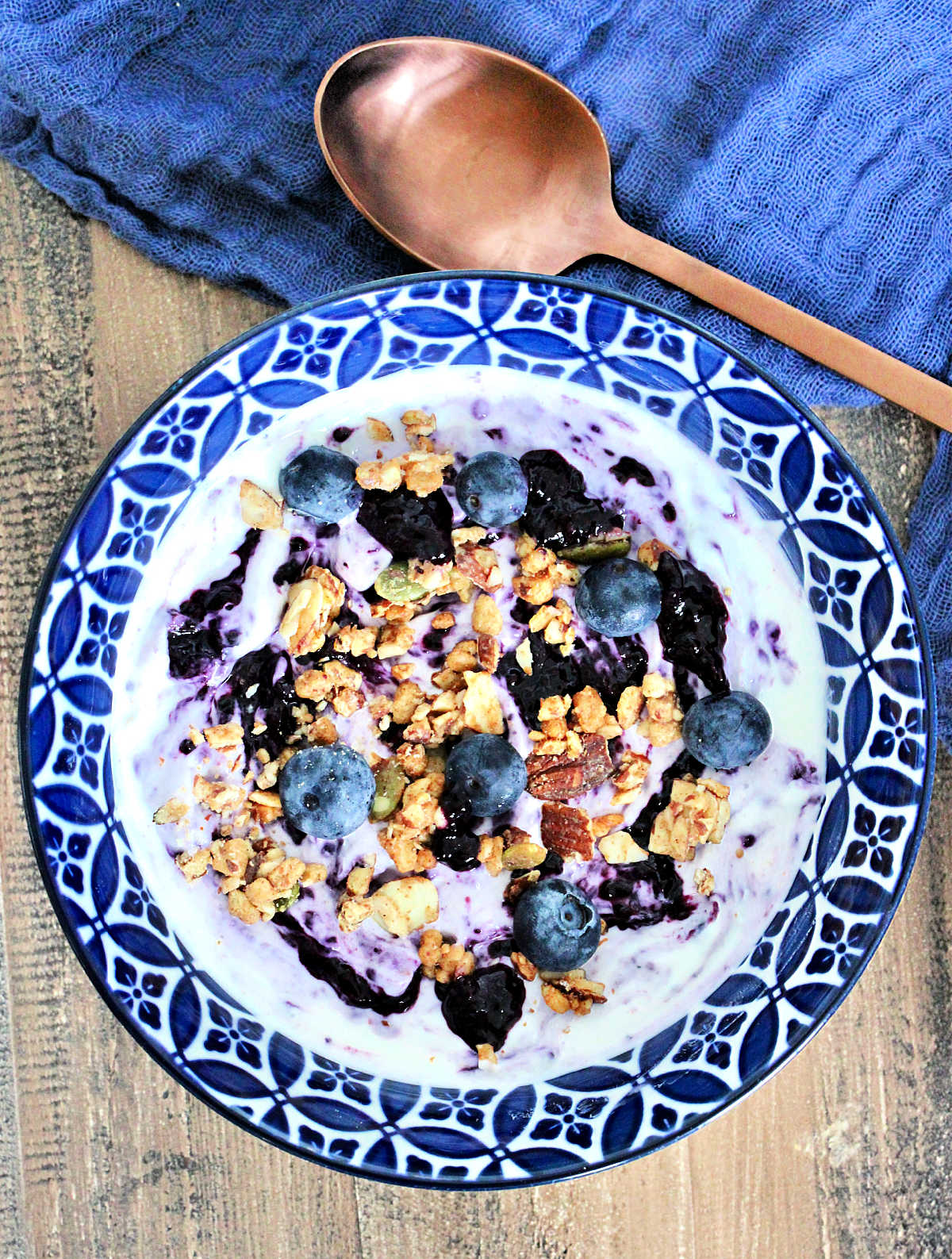 Blueberry chia jam swirled into a bowl of Greek yogurt topped with fresh blueberries and granola.