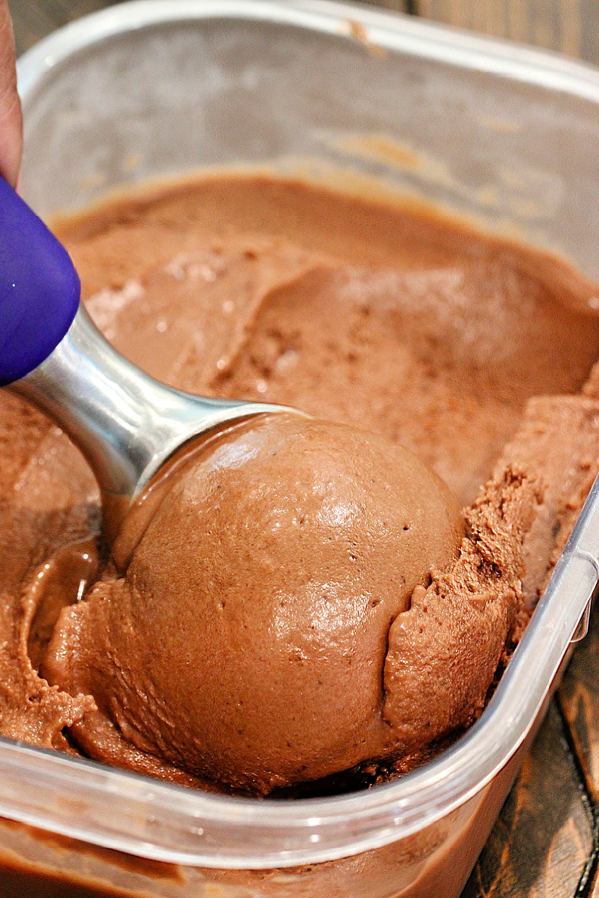 Healthy chocolate banana "ice cream" in a glass bowl topped with peanut butter, chocolate chips and crushed peanuts.
