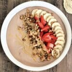 Chocolate protein yogurt bowl topped with banana, strawberry, granola and peanut butter.