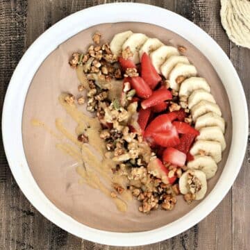 Chocolate protein yogurt bowl topped with banana, strawberry, granola and peanut butter.