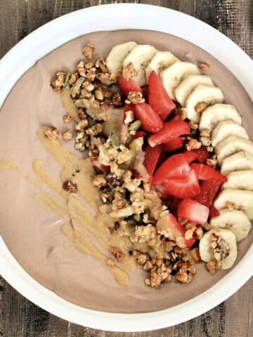 Chocolate protein yogurt bowl topped with banana, strawberry, granola and peanut butter.