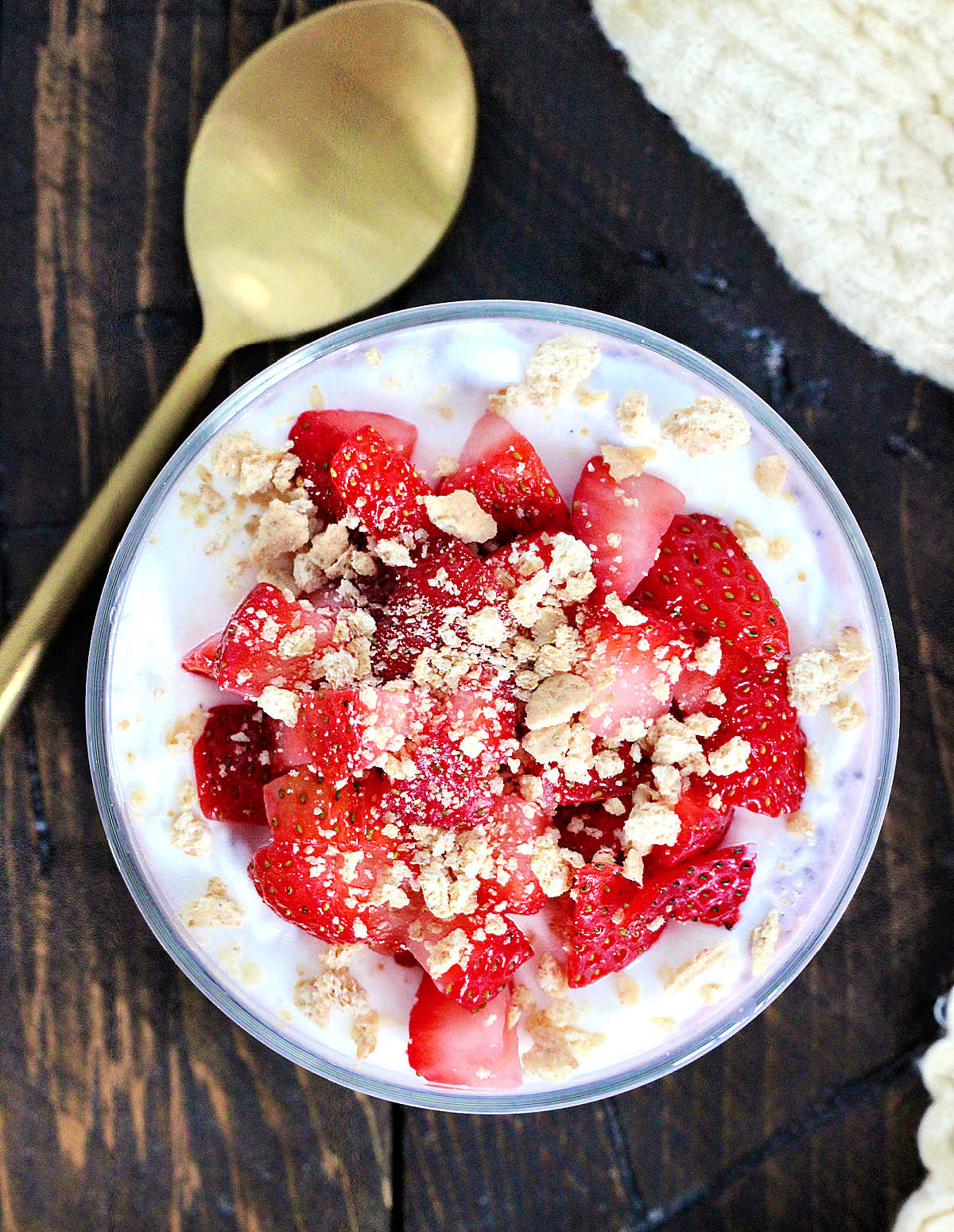 Strawberry cheesecake chia pudding in a glass topped with fresh strawberries and crumbled graham crackers.