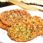 Pieces of avocado bread on a white plate with a gold knife and beige napkin in background.
