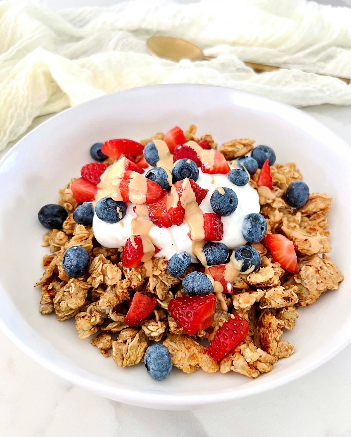 Scrambled oats in a white bowl topped with Greek yogurt and berries.