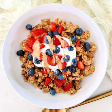 Scrambled oats in a white bowl topped with Greek yogurt and berries.