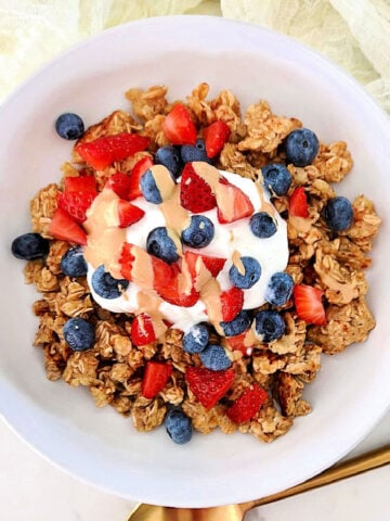 Scrambled oats in a white bowl topped with Greek yogurt and berries.