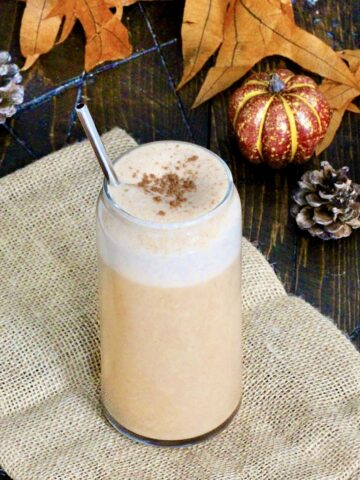 Pumpkin Spice Protein Shake surrounded by fall leaves and decorative pumpkins.