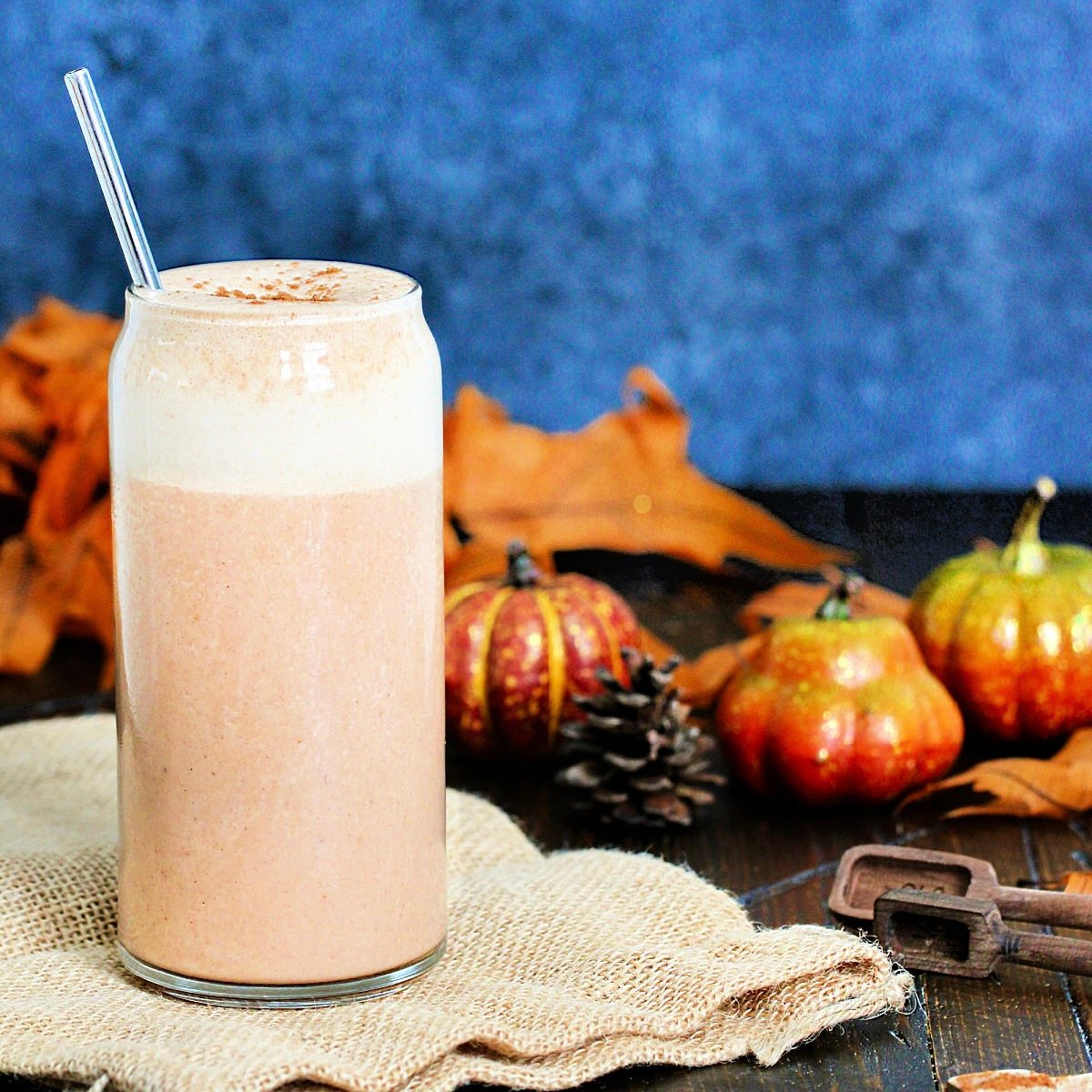 Pumpkin Spice Protein Shake surrounded by fall leaves and decorative pumpkins.