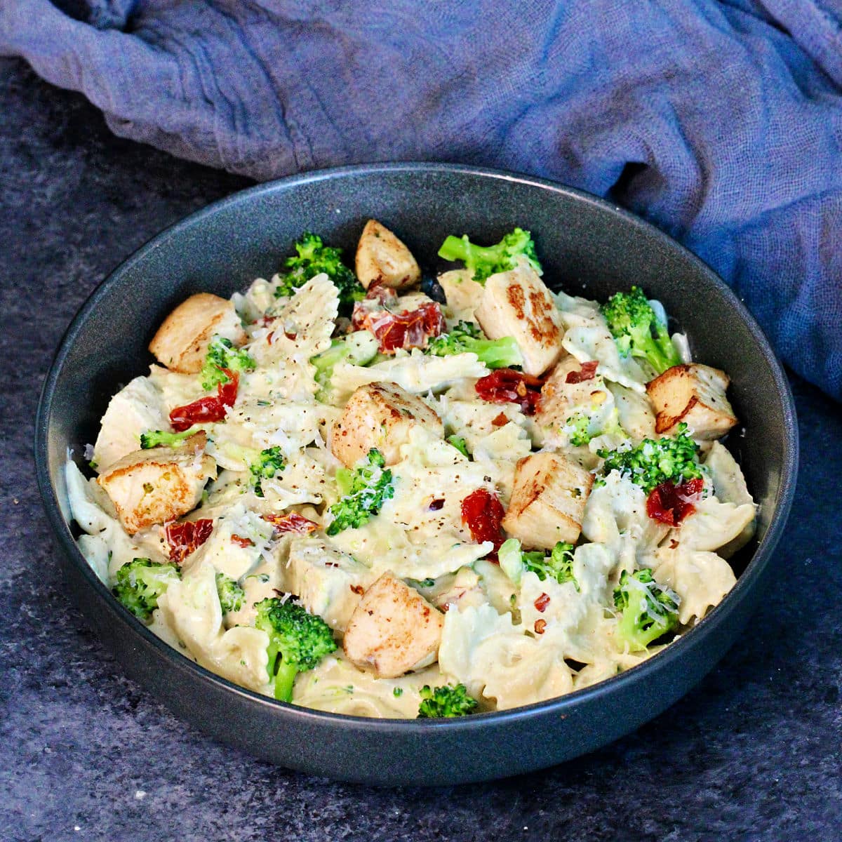 Pasta with Chicken and Creamy Cottage Cheese Sauce in a black bowl on a slate board.