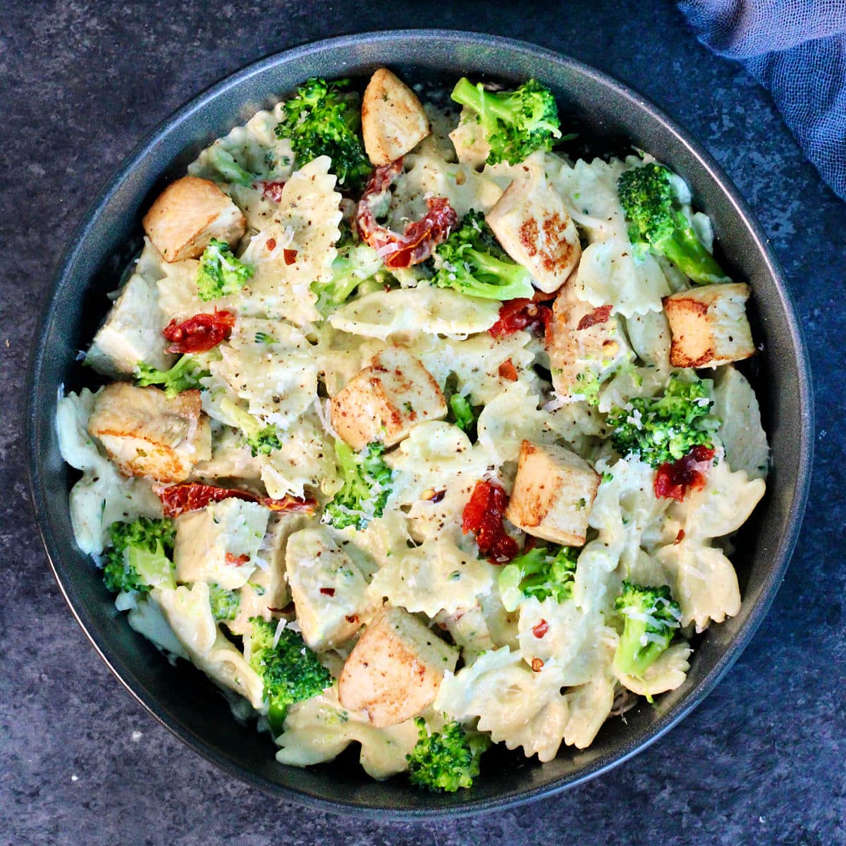 Pasta with Chicken and Creamy Cottage Cheese Sauce in a black bowl on a slate board.