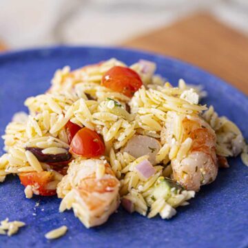 Shrimp and orzo on a blue plate.