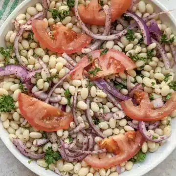 White bean salad in a white bowl.