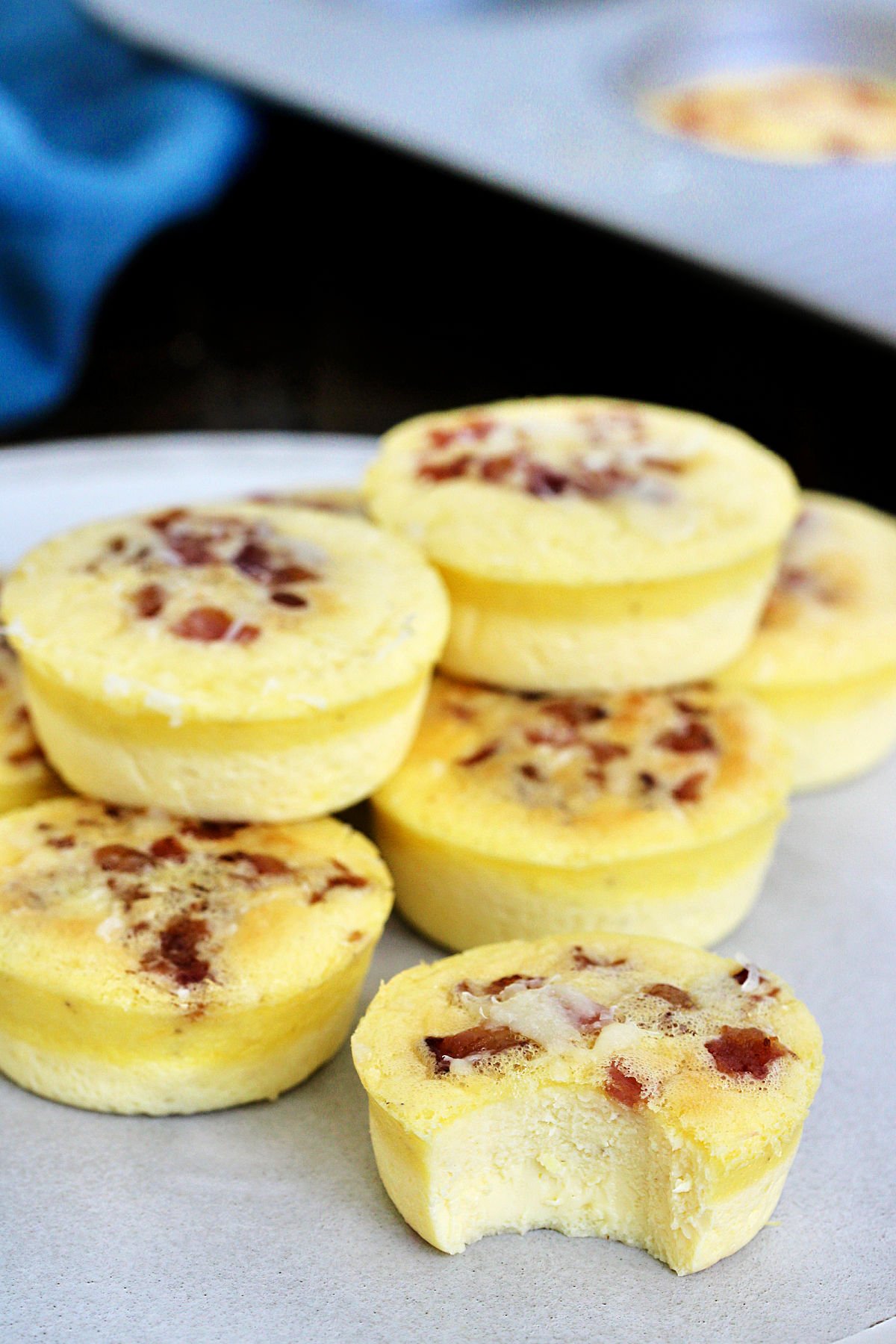 A stack of Starbucks copycat egg bites with bacon on a plate, one has a bite taken out of it.