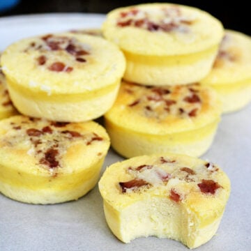 A stack of Starbucks copycat egg bites with bacon on a plate, one has a bite taken out of it.