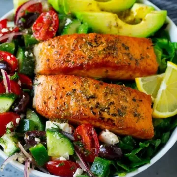 Two pieces of salmon on top of a salad.