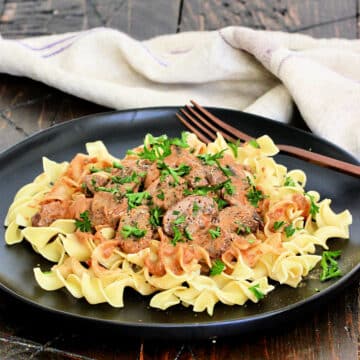 Mushroom Paprikash on a black plate on a wooden board.