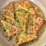Vegan tempeh piccata finished in skillet with lemon caper sauce