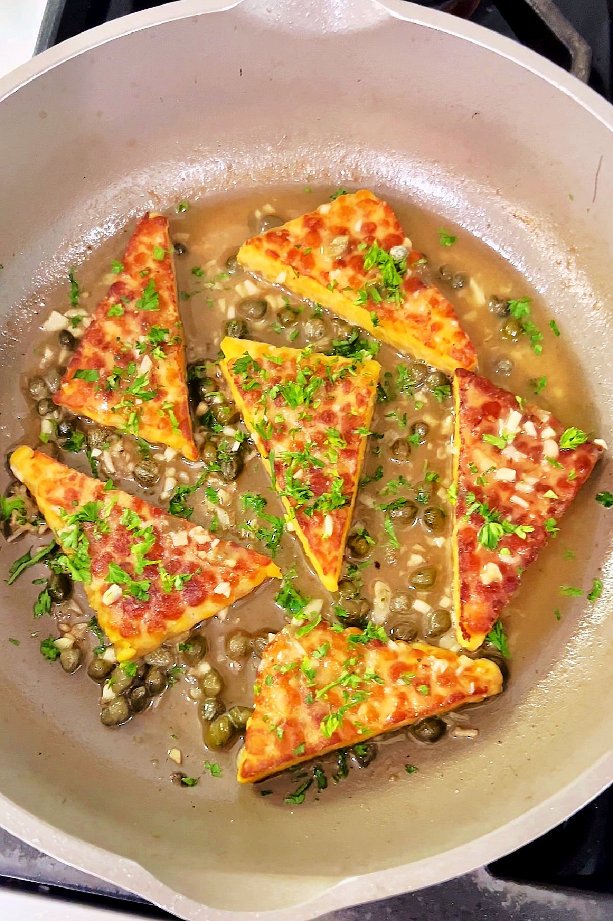 Vegan tempeh piccata finished in skillet with lemon caper sauce