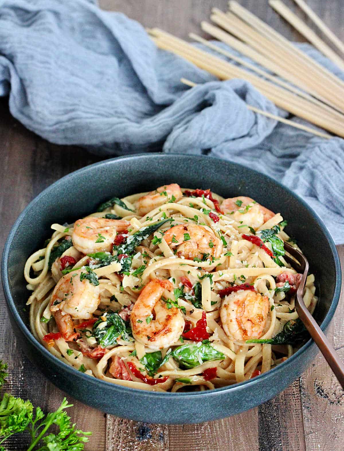 Shrimp and Spinach Pasta in a gray bowl on wooden board