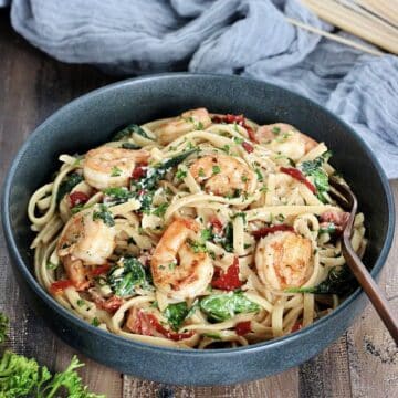 Shrimp and Spinach Pasta in a gray bowl on wooden board