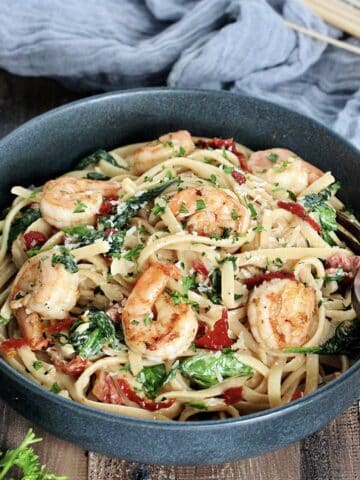 Shrimp and Spinach Pasta in a gray bowl on wooden board