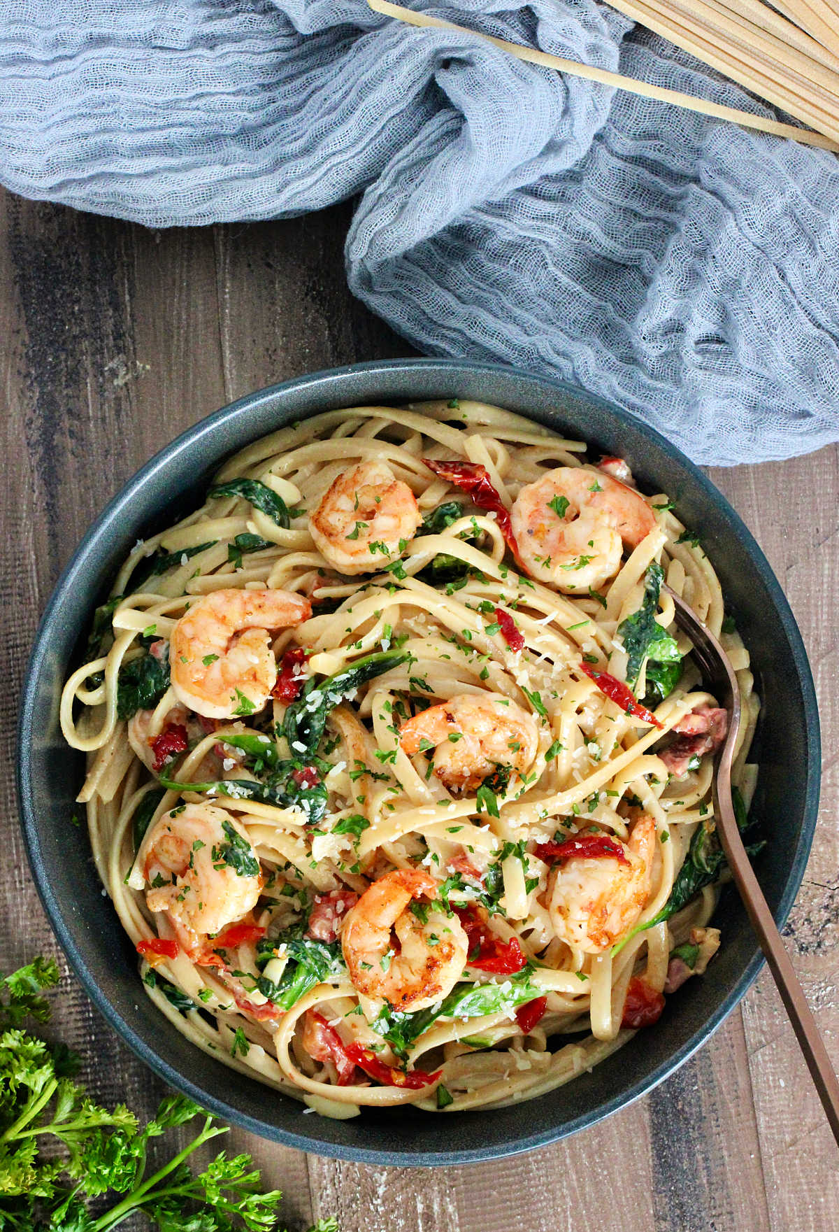 Overhead of Shrimp and Spinach Pasta in a gray bowl on wooden board